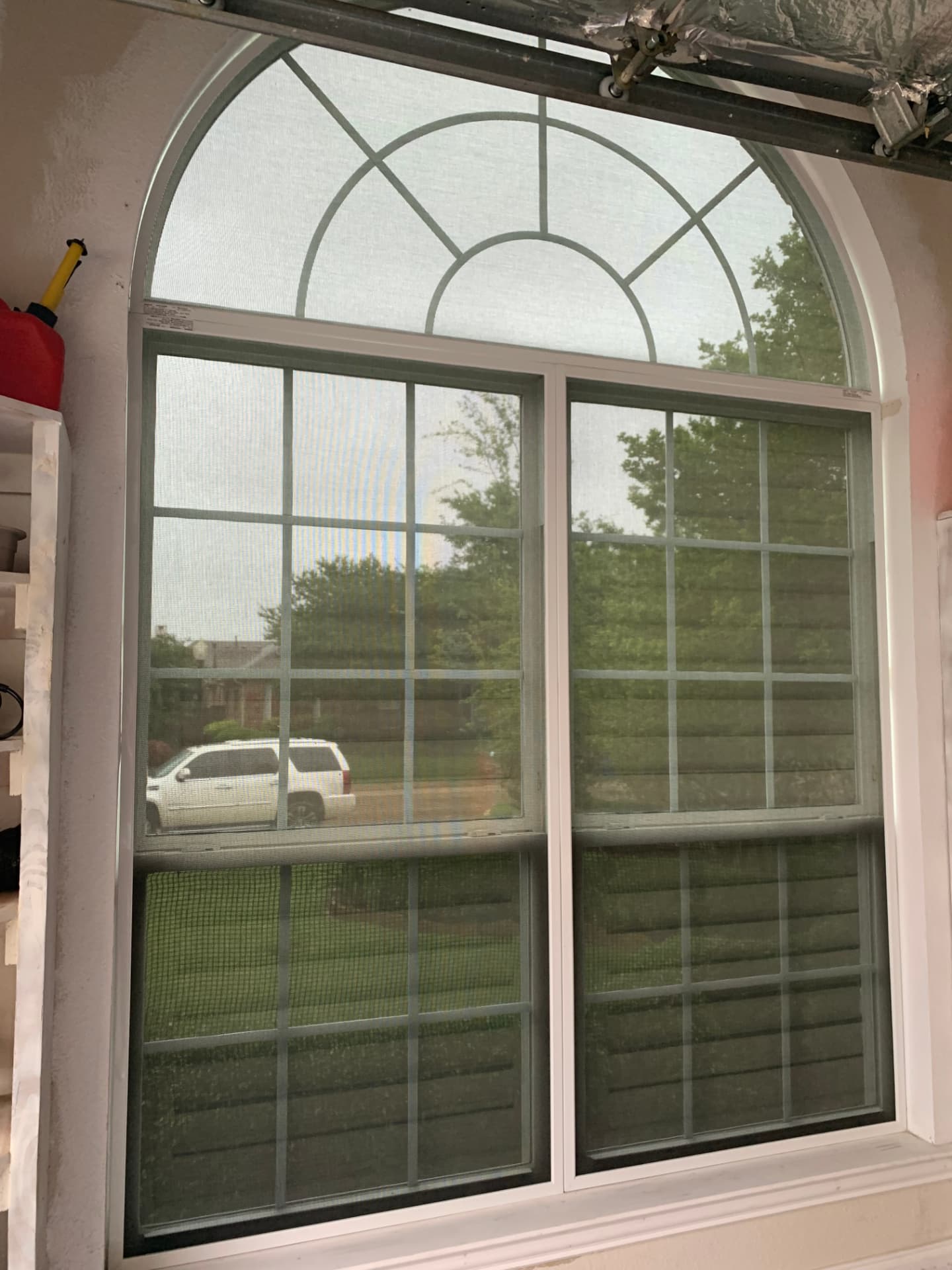Arched window with solar screen seen from inside a garage