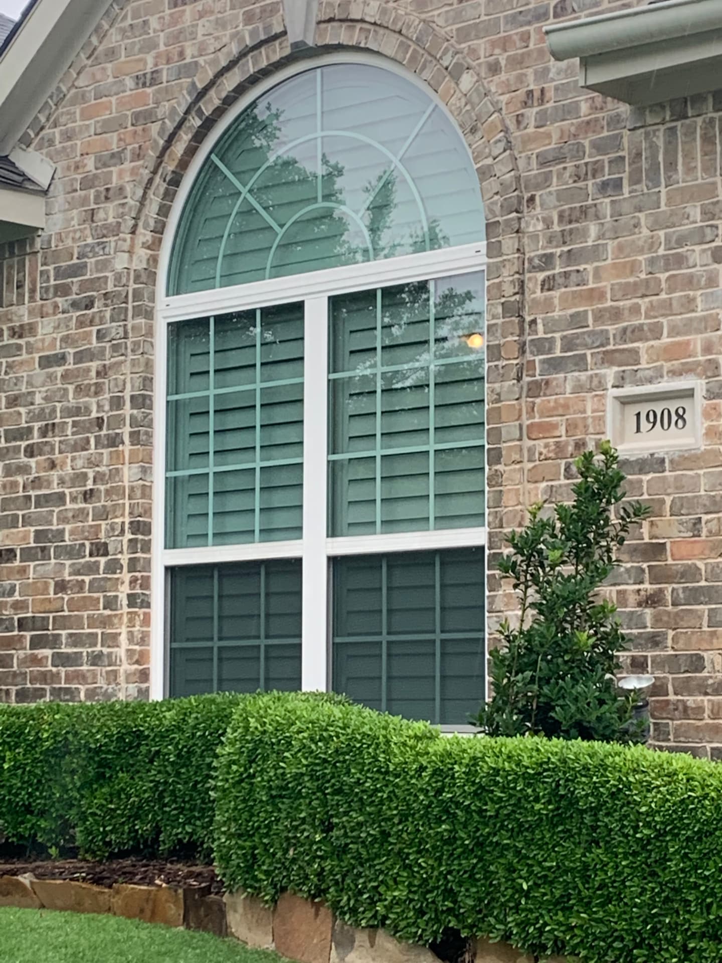 Brick home with tall arched window fitted with Optex solar screens